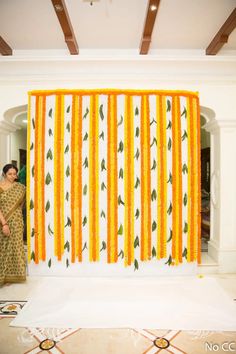 a woman standing in front of an orange and white curtain