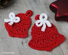 two crocheted red and white christmas hats sitting on top of a wooden table