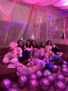 four women sitting on a couch with stuffed animals and balloons in front of the room