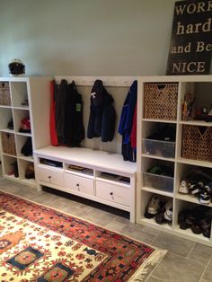 a room filled with lots of white shelves next to a rug and shoes on the floor