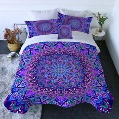 a bed with purple and blue designs on the comforter, pillows and pillow cases