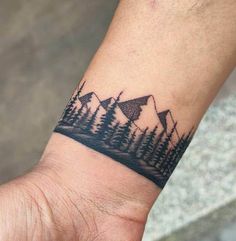 a person's wrist with a small mountain scene tattoo on the left side of their arm