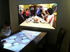 two children are looking at a large screen with food on it in front of them