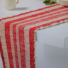 a red and white striped table runner on top of a counter next to some plates