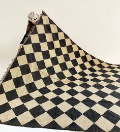 a person standing on top of a black and white checkered blanket with a cowboy hat