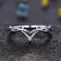 a white gold ring with three stones on it's sides and two leaves in the middle