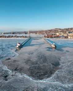 two boats are on the frozen water in front of a bridge