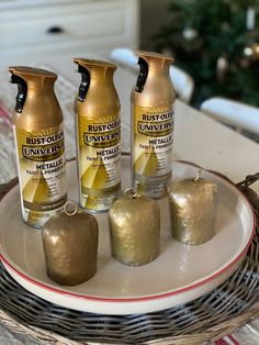 three bottles of paint sitting on top of a white plate next to two gold apples