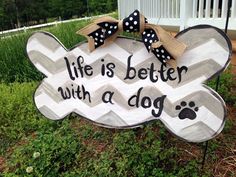 a wooden sign that says life is better with a dog and has a bow on it