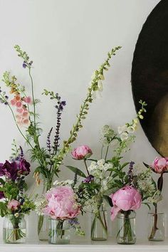 vases filled with flowers sit on a mantle