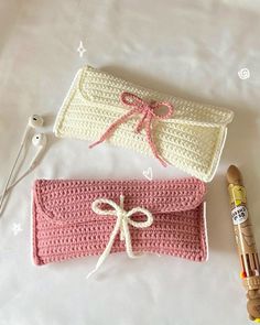 two crocheted purses sitting on top of a bed next to an earphone