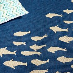 a blue blanket with white fish on it and a chevron pillow in the background