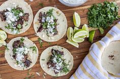 four tortillas on a cutting board with limes and cilantro