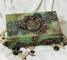 an ornate wooden box sitting on top of a white cloth covered tablecloth with keys and charms