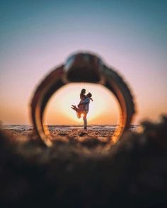 a person standing on the beach in front of an object that looks like a ring