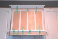 some green tape is taped to the top of a window sill in a kitchen