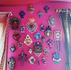 a pink wall covered in lots of different types of brooches