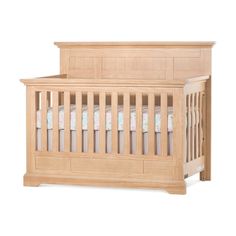 a wooden baby crib with white sheets and pink bedding on the bottom half