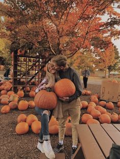 two people are hugging each other in front of pumpkins on display at the park