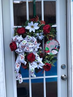 a wreath on the front door decorated with red roses and white lilies for christmas