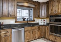 a kitchen with wooden cabinets and stainless steel appliances, including a dishwasher in the center