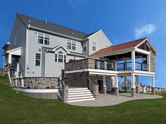 a two story house with stone and brick sidings on the front porch, stairs leading up to the second floor