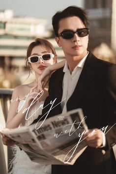 a man and woman in sunglasses are standing next to each other, reading the paper