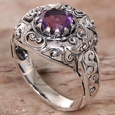 Designed and crafted by Indonesian artisan Agung Jagra this ring features a 1.5 carat amethyst. Sterling silver leaf and swirl designs outline the faceted stone and twist down the side of the ring's band. Purple Amethyst Ring With Intricate Design, Purple Amethyst Ring With Intricate Design For Promise, Purple Amethyst Promise Ring With Intricate Design, Sterling Silver Amethyst Promise Ring With Intricate Design, Purple Promise Ring With Intricate Design, Purple Intricate Design Promise Ring, Ornate Amethyst Purple Ring, Ornate Amethyst Gemstone Ring, Ornate Purple Amethyst Ring