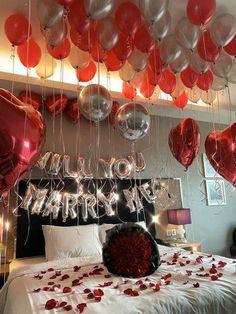 balloons and streamers are hanging from the ceiling above a bed