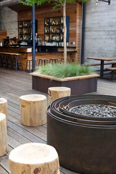 several wooden stools sitting on top of a wooden deck next to tables and chairs