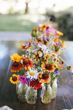 several mason jars filled with colorful flowers on a table