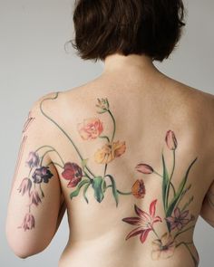 a woman with flowers on her back is shown from the waist up, and there are no visible tattoos