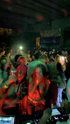 a group of people standing around each other in front of a dj's mixer