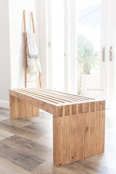 a wooden bench sitting on top of a hard wood floor next to an open door