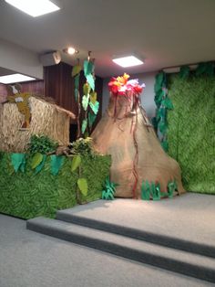 the stage is decorated with grass and flowers for an outdoor play area that looks like it could be used as a jungle theme