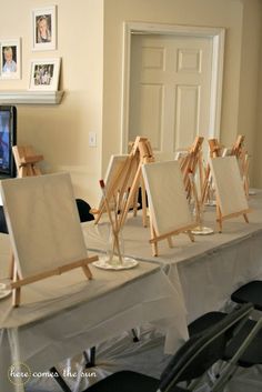 several easels are lined up on a table in front of a television and pictures