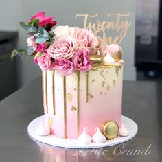 a pink and gold cake with flowers on top