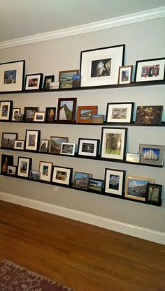 a wall filled with lots of framed pictures on it's sides next to a wooden floor