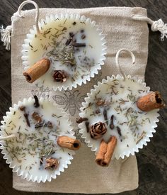 two cups filled with different types of spices on top of a cloth bag next to cinnamons