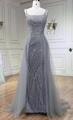 This  silver bead embellished gown with an overskirt is a show-stopping piece that exudes luxury and elegance. The gown is intricately adorned with shimmering silver beads, creating a dazzling effect that catches the light beautifully. The fitted silhouette of the gown enhances the natural curves, while the attached overskirt adds a dramatic and voluminous element, creating a sense of grandeur. This combination of the sleek, bead-embellished base and the flowing overskirt results in a balanced and captivating look, perfect for making a lasting impression at any formal event or gala. Production time is between approx 6-8 weeks. * Sizing - All items are made according to measurement ranges, they are NOT typical letter or numeric sizing. It is imperative to compare your exact measurements wit Silver Wedding Dress Older Bride, Silver Gowns Elegant, Silver Dresses Elegant, Silver Dress Formal, Elegant Silver Dress, Farewell Dance, Overskirt Dress, Silver Ball Gown, Silver Wedding Gowns