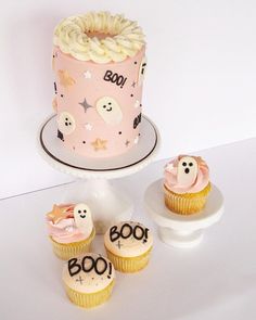 a cake and cupcakes are sitting on a white table with the word boo spelled out