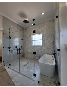 a bathroom with a tub, shower and glass walls that are reflecting the light coming in from the window