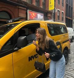 a woman standing next to a yellow taxi