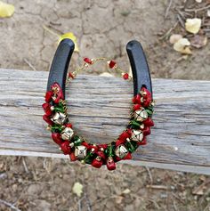 a necklace with bells and red flowers on it sitting on a wooden bench in the grass