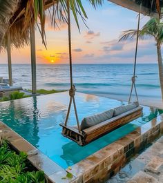 a hammock hanging from the side of a swimming pool near the ocean at sunset