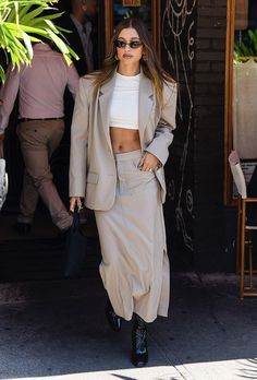 a woman in a skirt and jacket walking out of a building with her hand on her hip