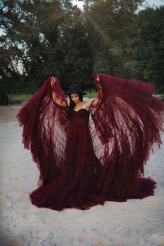 a woman in a red dress is standing on the sand