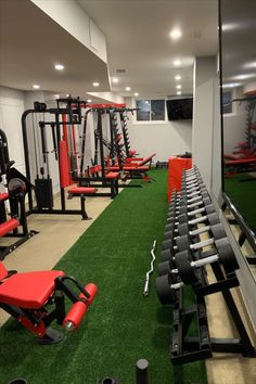 a gym with rows of exercise equipment and green carpeted flooring in front of windows