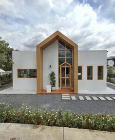 a white house with wood trim and windows on the front door is surrounded by greenery