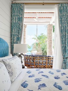 a bed sitting in a bedroom next to a window covered in blue and white curtains